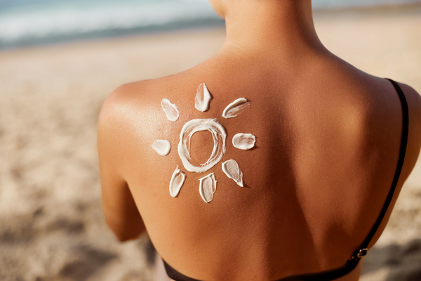crema de protectie solara aplicata in forma de soare pe spatele unei femei